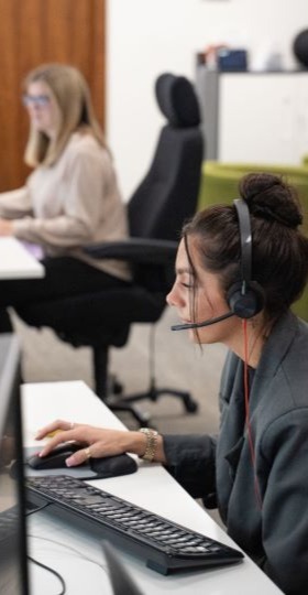 Two emergency call centre operatives taking calls whilst stat as their desks.
