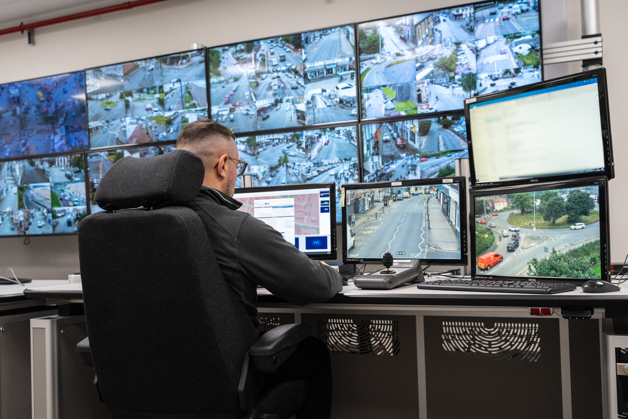 CCTV controller working at a bank of monitors.
